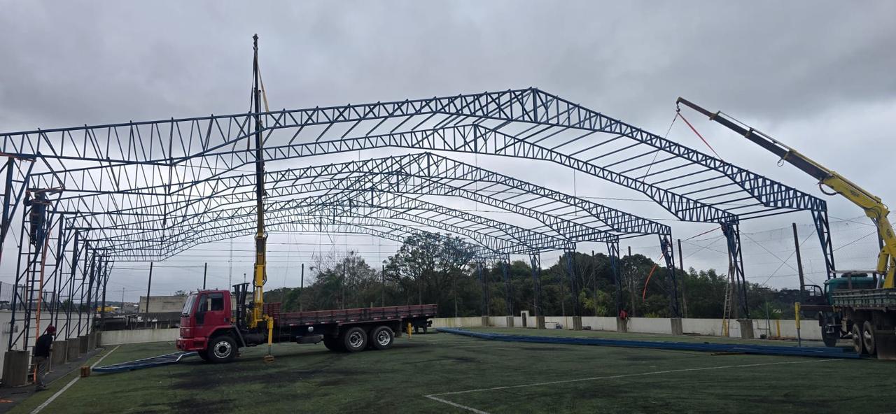 Içamento de tesouras metálicas por caminhão munck durante a montagem de quadra esportiva coberta